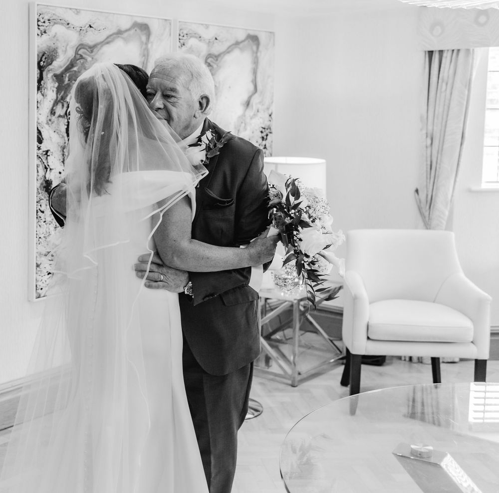 Intimate black and white moment between a bride in her veil and a formal-dressed elder.