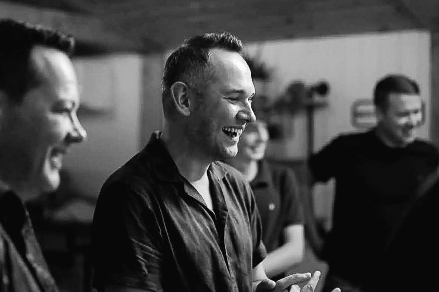 Black and white candid photo showing genuine laughter during pre-wedding preparations.