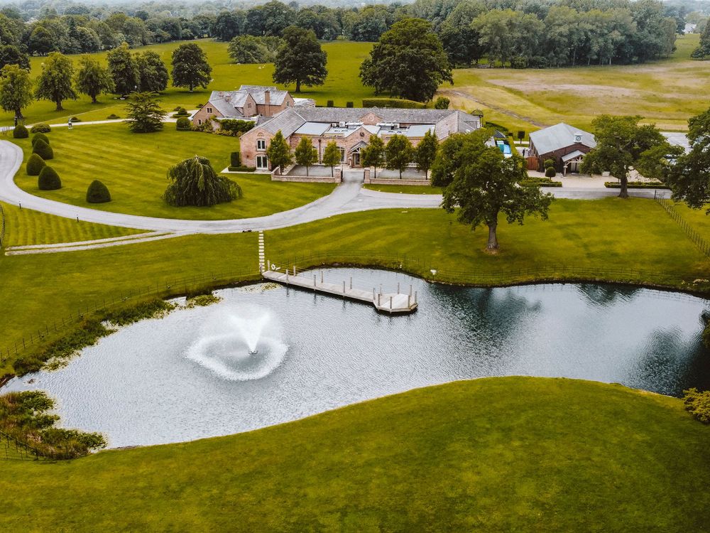 Aerial view of an elegant wedding venue with manicured grounds and heart-shaped pond.