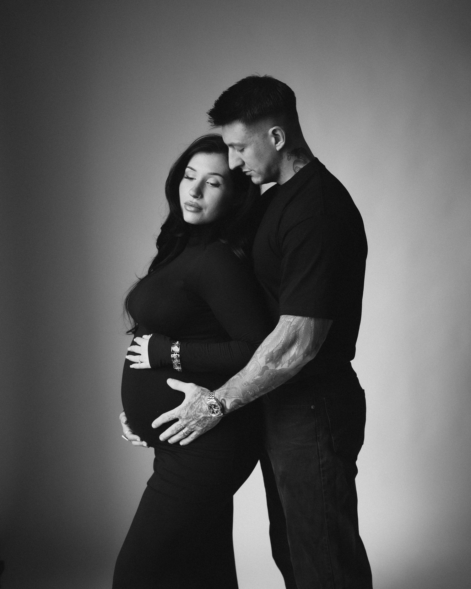 A series of four intimate black and white portraits showing a couple embracing in silhouette against a dark background.