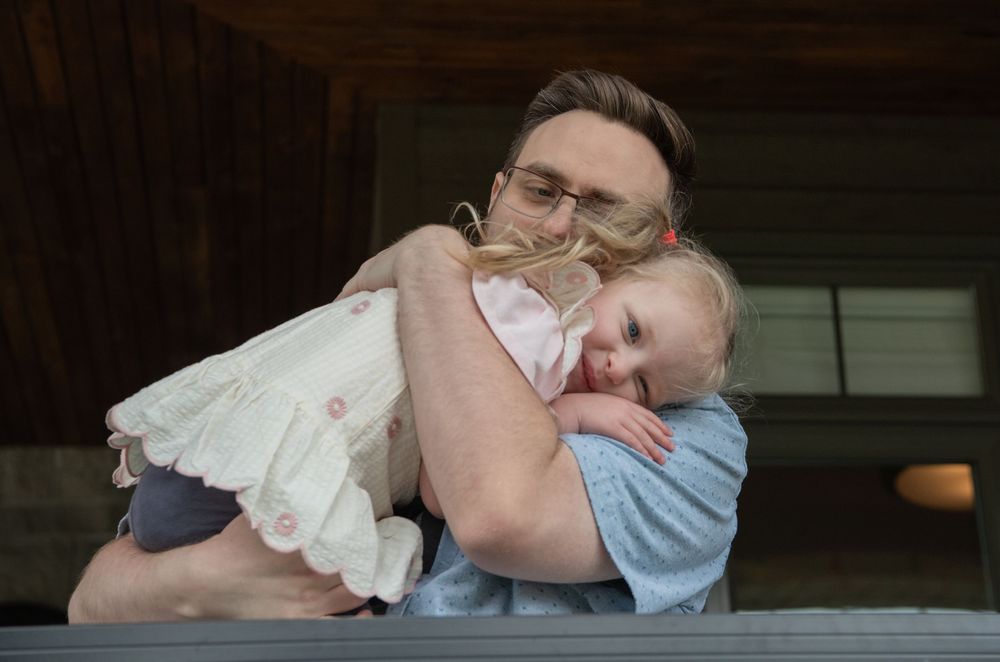 A tender moment of comfort and connection as two people embrace on a wooden porch.