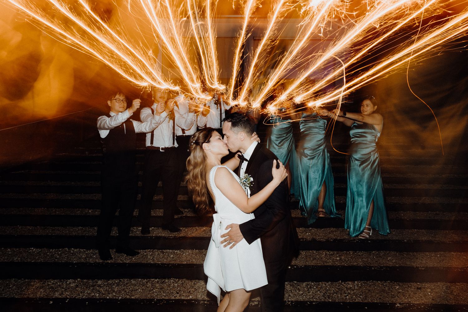 A couple shares a romantic dance moment at night with sparklers captured by Apertured Media Auckland Wedding Photographer.