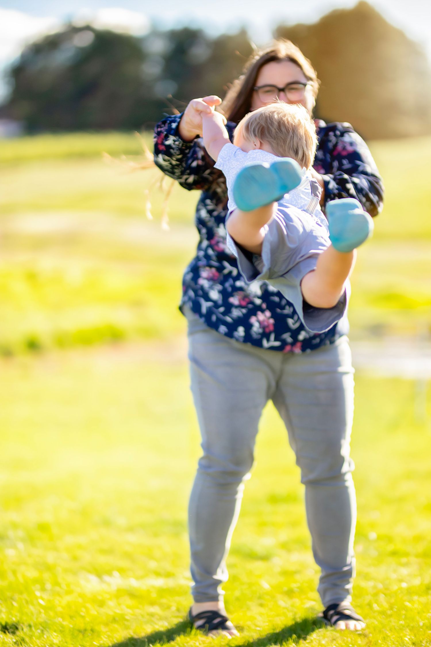 Mom swings son around by the arms on a warm sunny evening during a family photography session in Ellensburg, WA