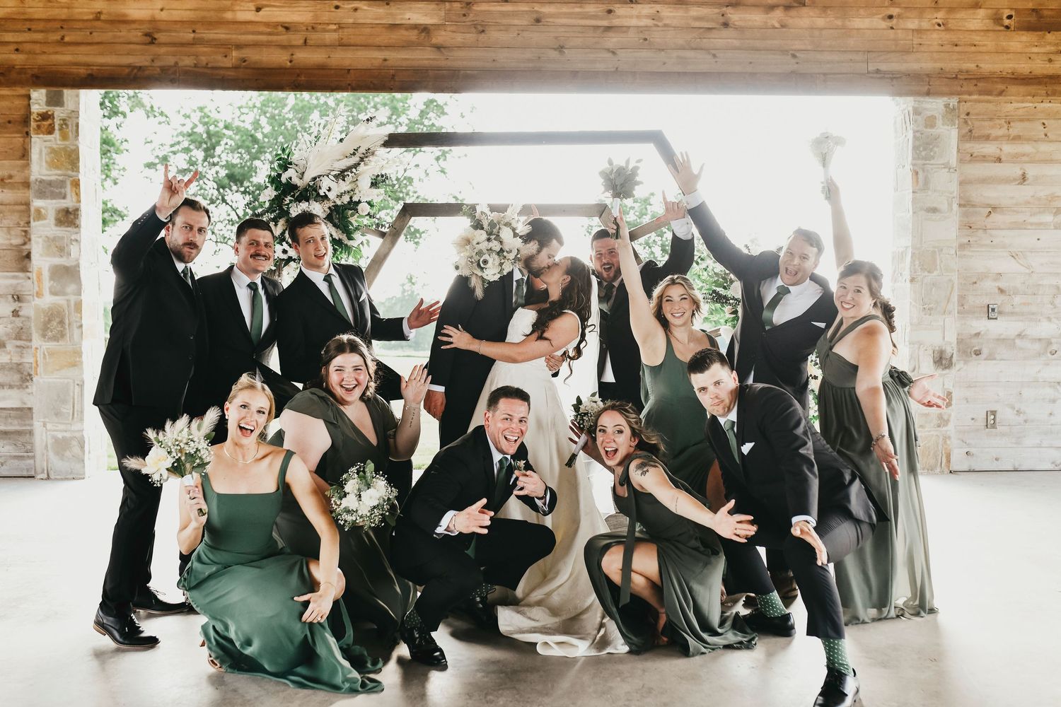High-energy wedding party cheering with arms raised at The Madelyn