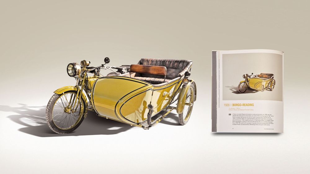 A vintage yellow motorcycle with sidecar displayed alongside a vintage print in a museum setting.