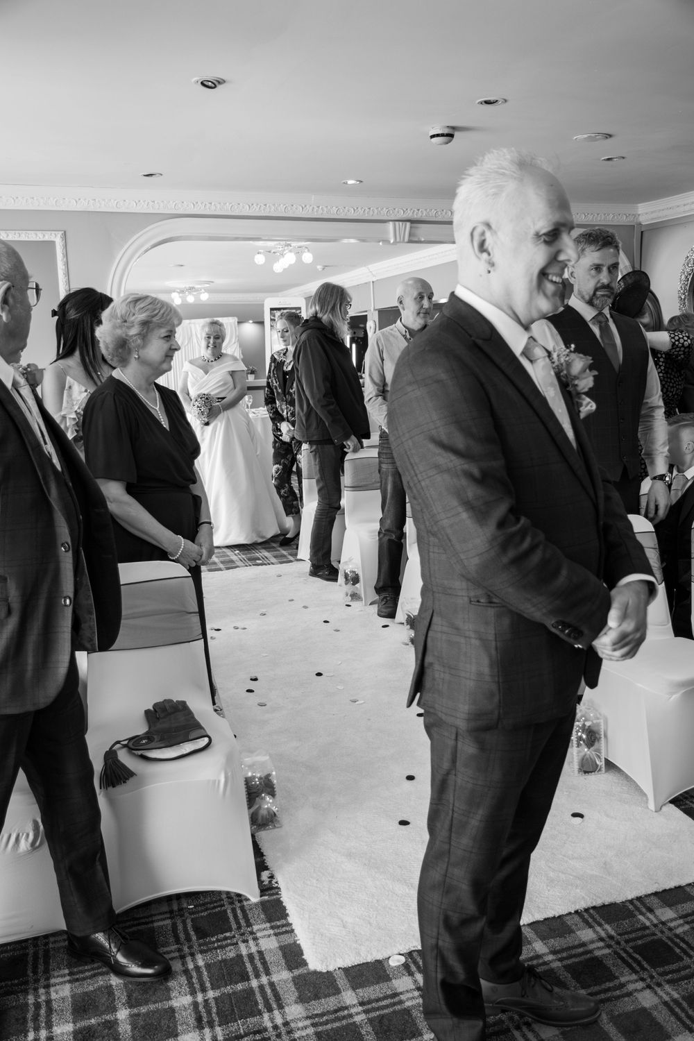 Guests gathered at a formal event in an elegant room with plaid carpet and recessed lighting in the ceiling.