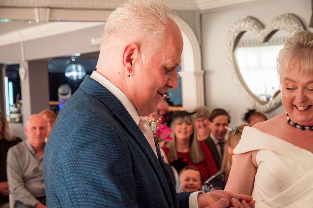 Two people share a tender moment during a wedding ceremony as an exchange of rings takes place.