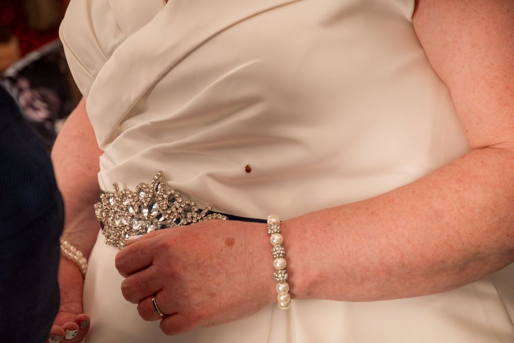 Close-up photo of an ornate crystal tiara and pearl bracelet worn with a white gown at a formal event.