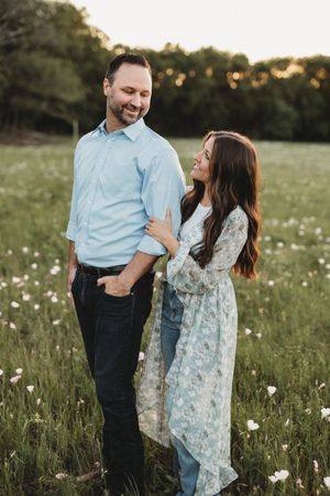 A couple shares a romantic moment in a wildflower meadow at sunset wearing coordinating blue outfits.