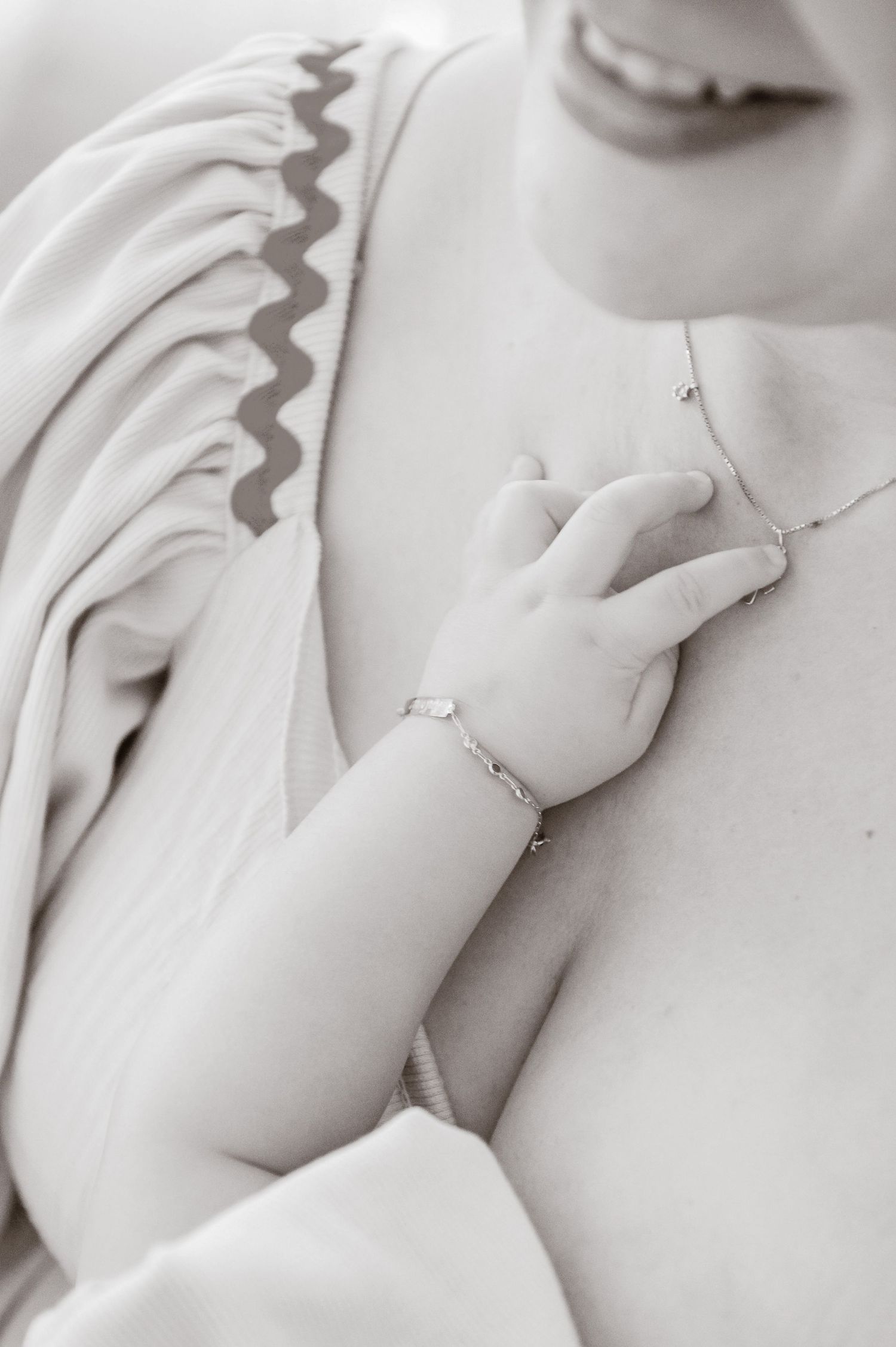 A monochromatic portrait showing delicate hands wearing jewelry and a white draped fabric creating soft shadows.