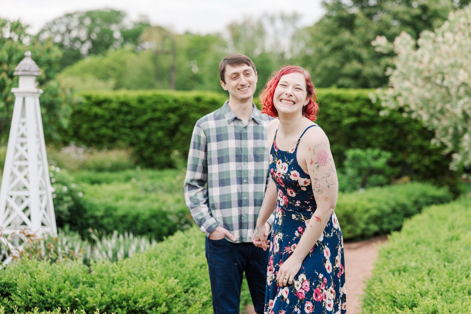 A couple stands together on a garden path with a white decorative obelisk and lush greenery in the background at Cantigny Park