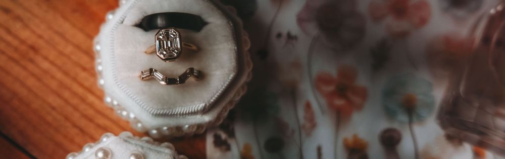 A closeup macro shot of a Chanel branded macaron in white and gray tones with blurred floral background.