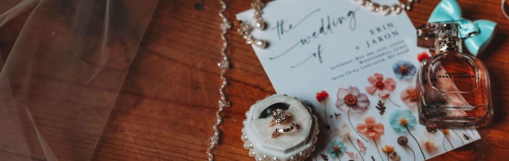 An elegant flatlay with perfume bottle, jewelry, and floral petals on a rustic wooden surface.