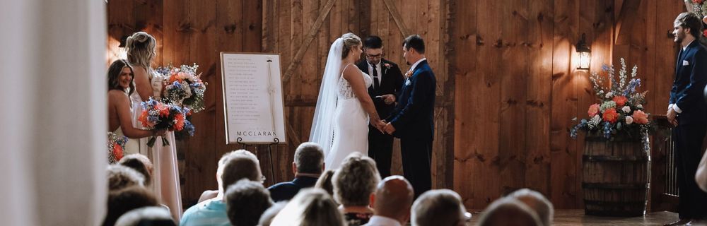 Wedding ceremony in a rustic wooden venue with guests seated watching couple exchange vows.