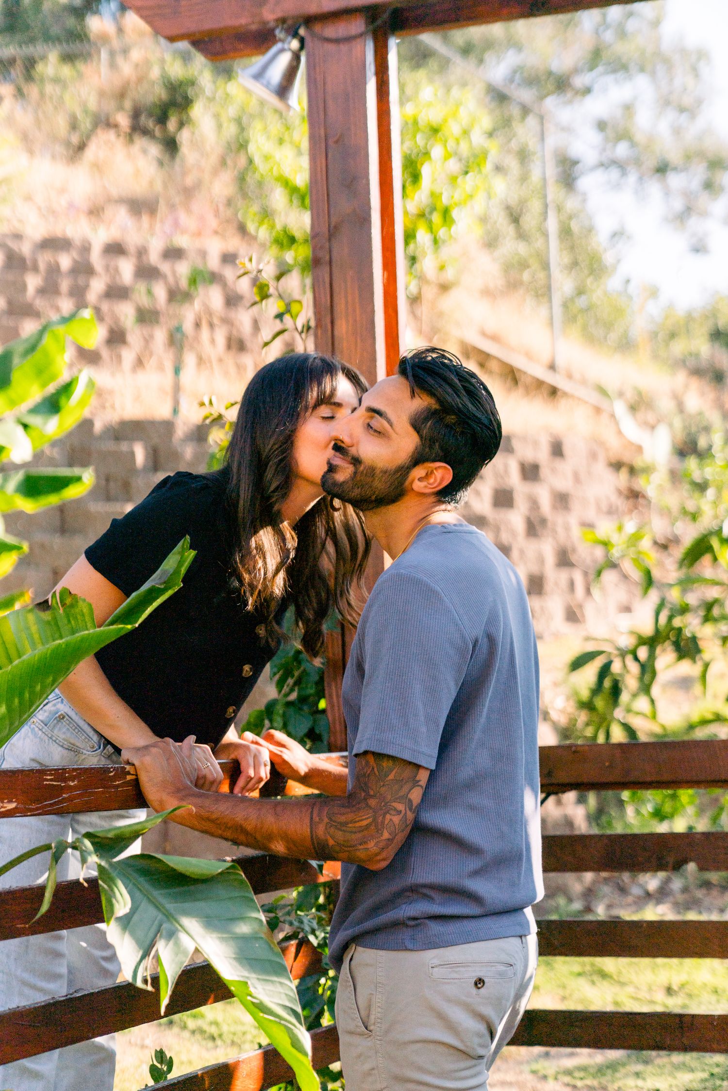A couple sharing a romantic moment on an outdoor terrace surrounded by tropical plants.