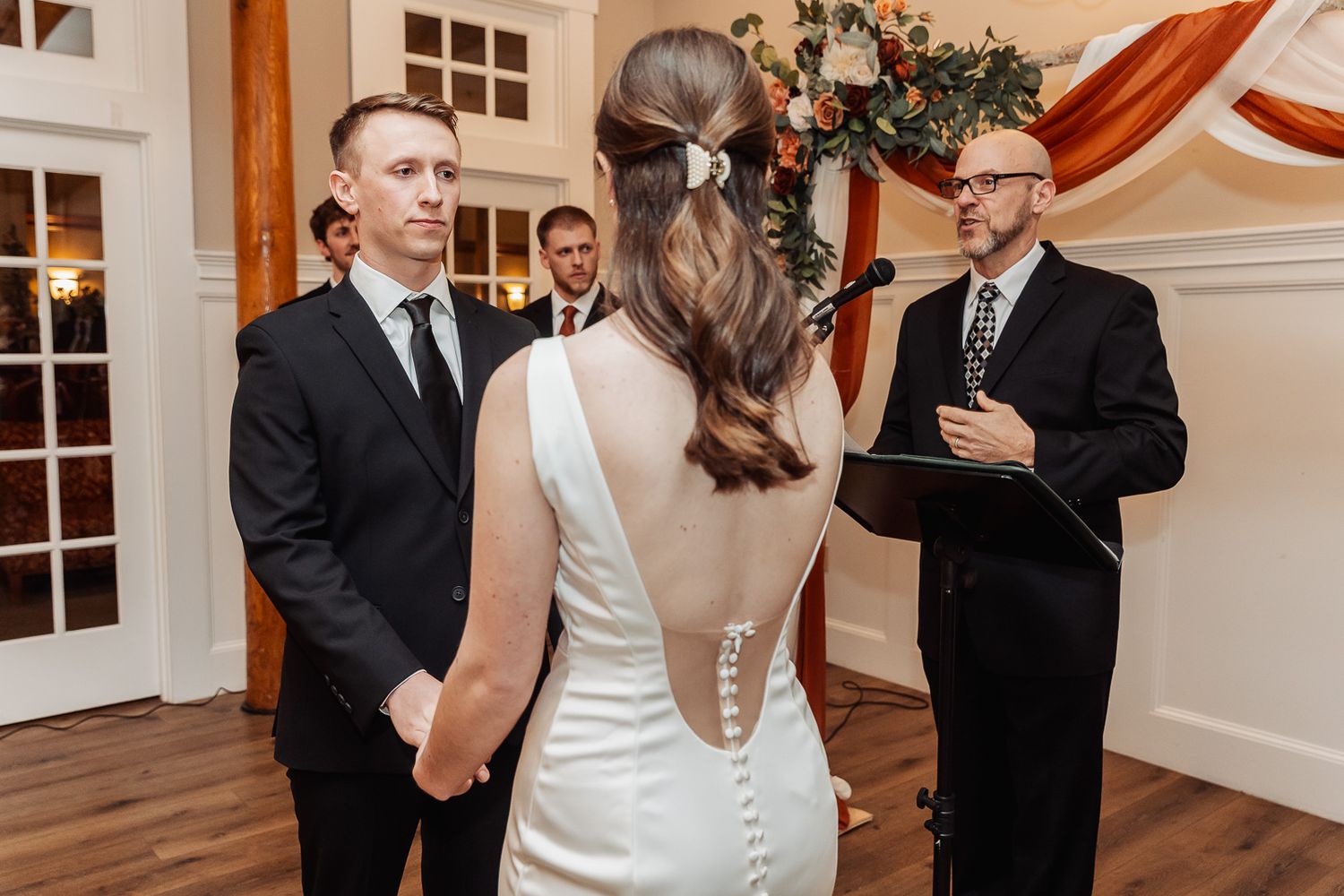 Wedding ceremony in progress with couple exchanging vows in front of officiant.