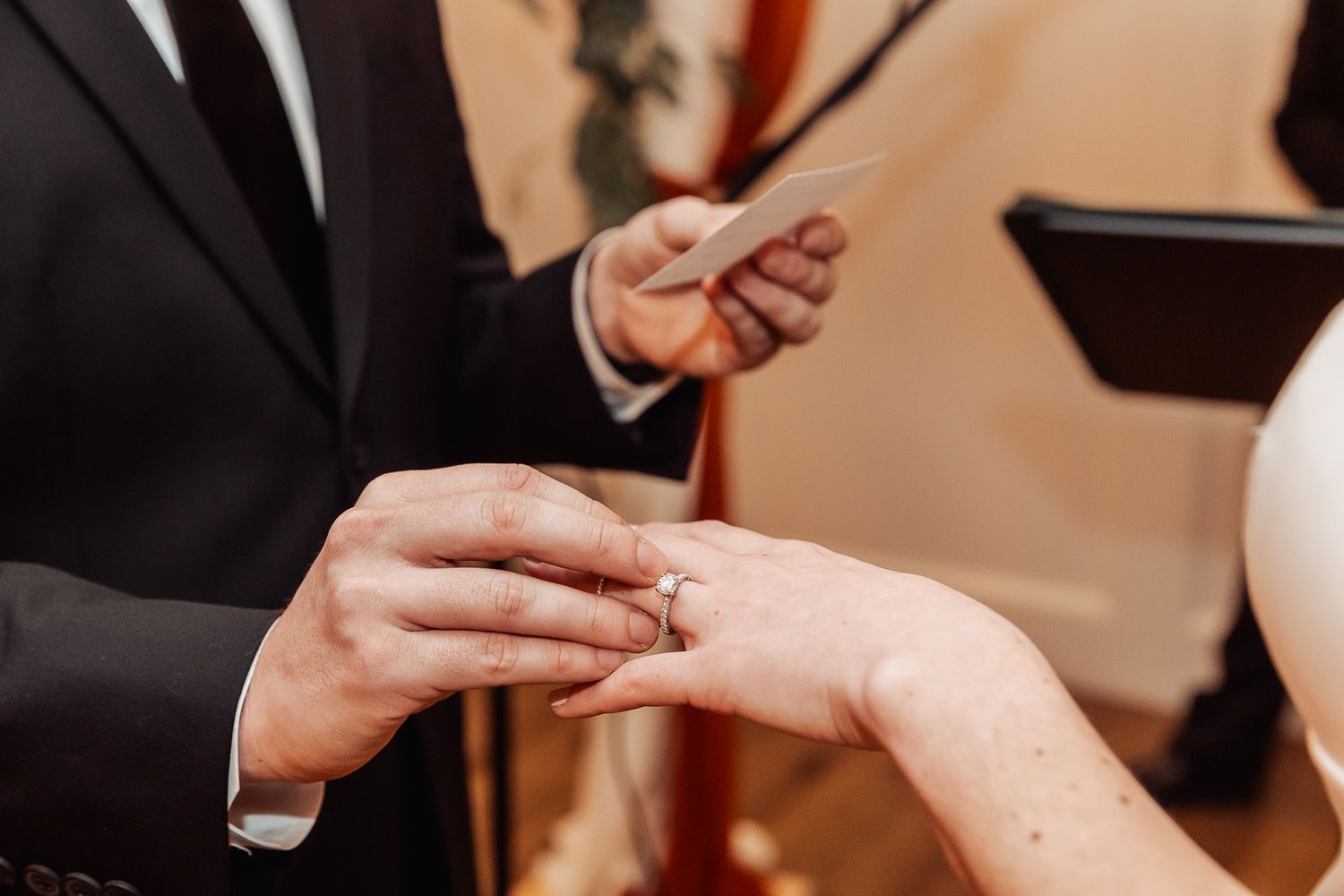 Close-up shot of hands during a wedding ceremony as a ring is placed during the exchange of vows.