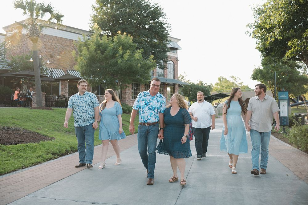 A group of people walking down a paved walkway at dusk on a summer evening.