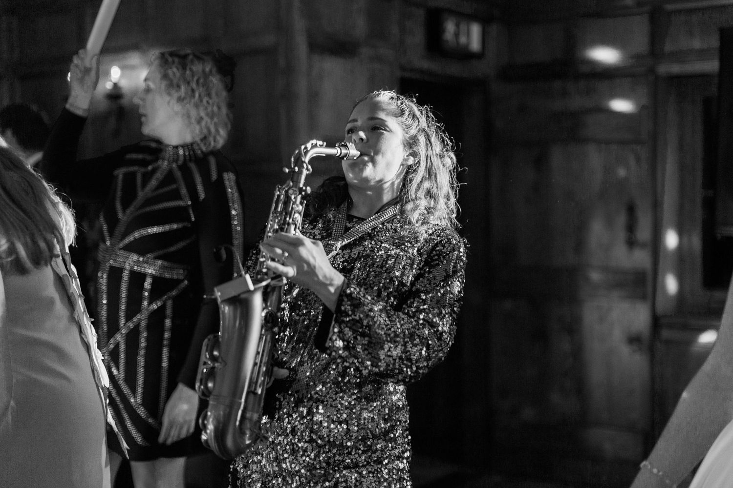 A saxophonist in a sparkling sequin dress plays passionately on a dimly lit stage at Deer Park Hall Hayley Elizabeth Photography