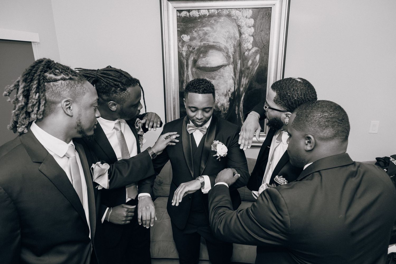 Candid black and white photo of groomsmen sharing laughs and celebrations before wedding.