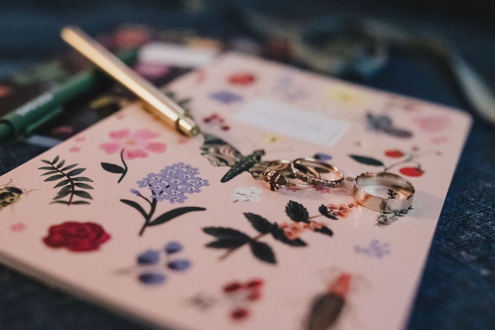 Close-up of pink notebook with delicate floral and insect illustrations.