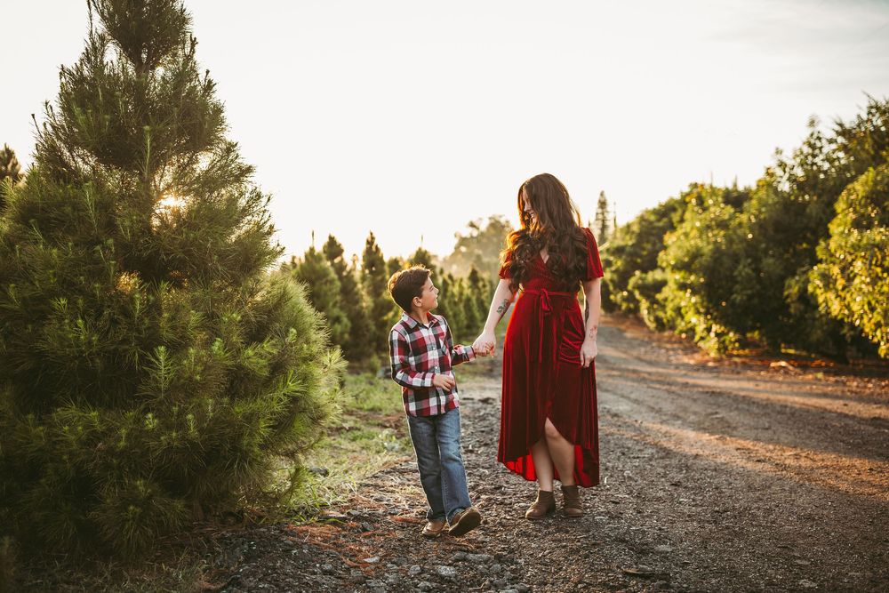 Candid outdoor family portraits captured along a tree-lined path with beautiful golden hour lighting.