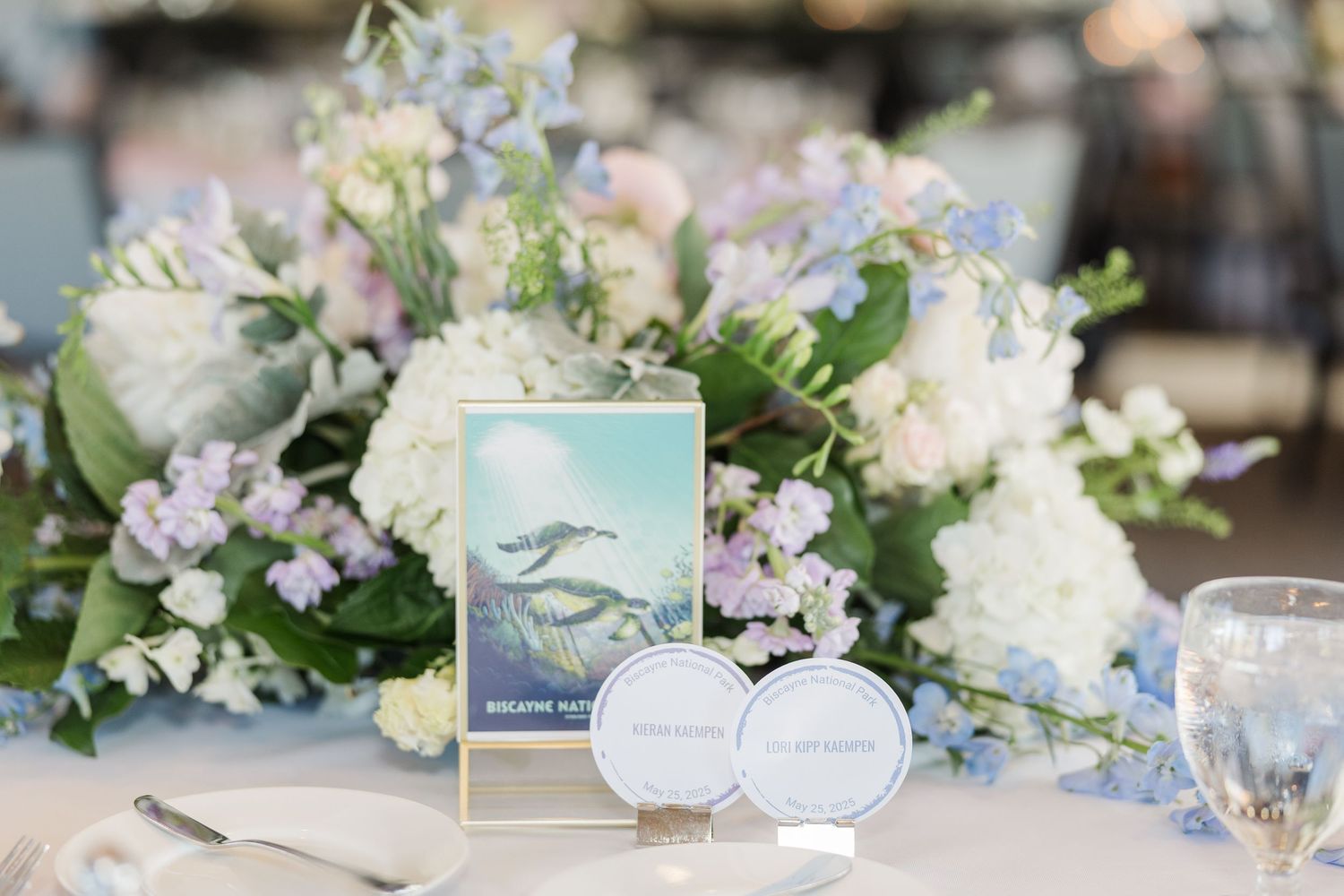 Elegant wedding table setting with white floral centerpiece, light blue place card and delicate ring box.