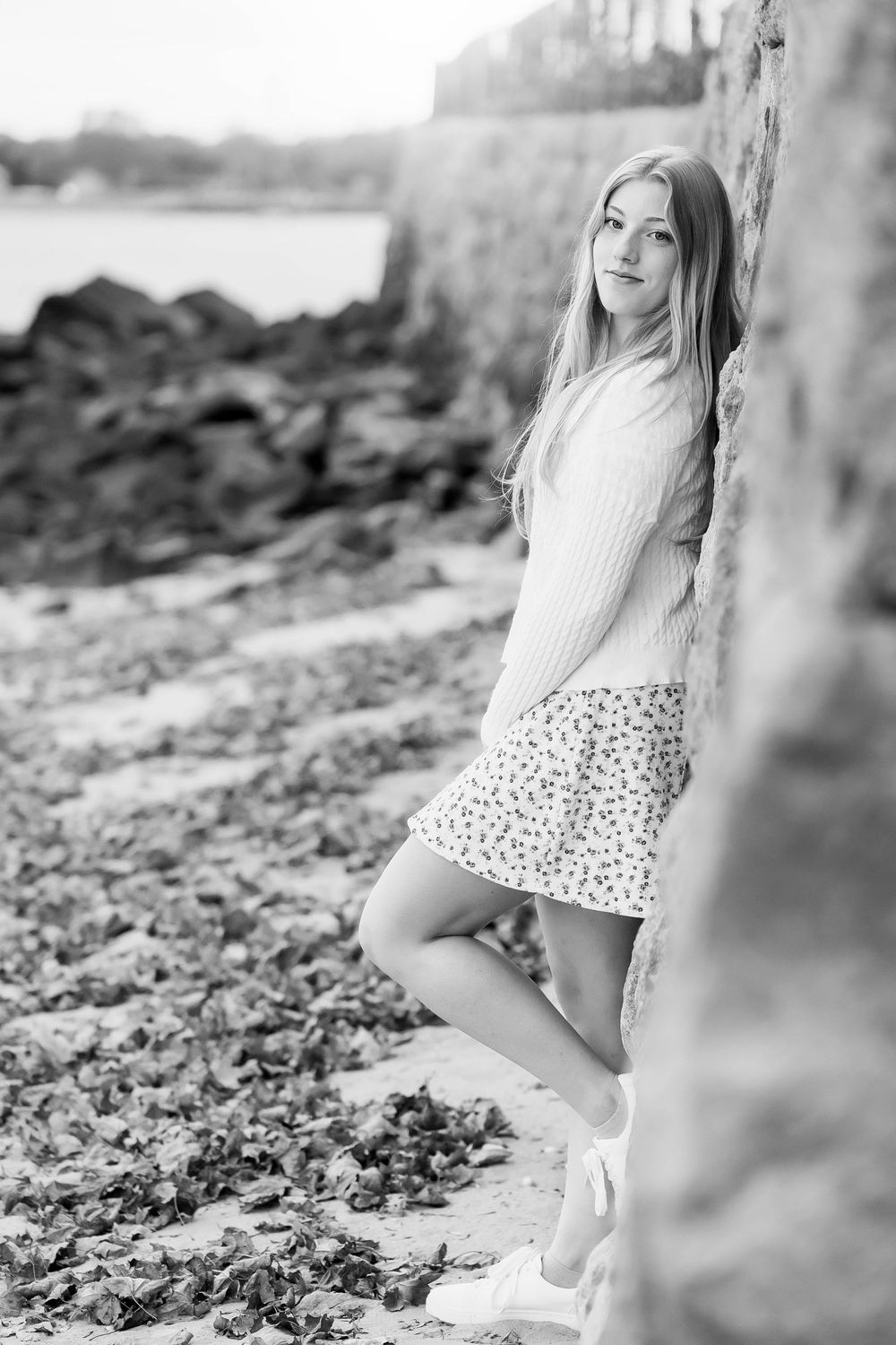 A series of black and white photos showing someone sitting outdoors in a floral dress and sneakers.
