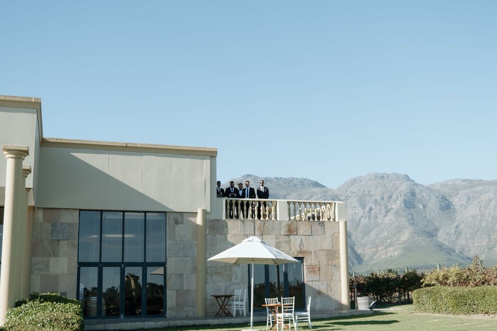Modern coffee shop building with white umbrella seating and mountains in the background at a winery estate.