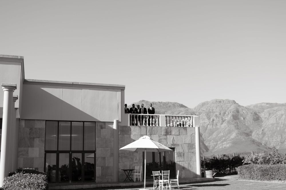 Modern restaurant building with white umbrella and prominent signage against mountain backdrop in black and white.