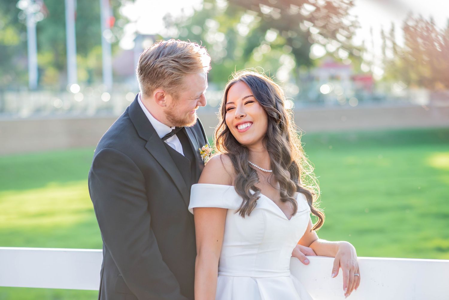A couple shares a romantic outdoor moment in a green park setting during a wedding photo session.