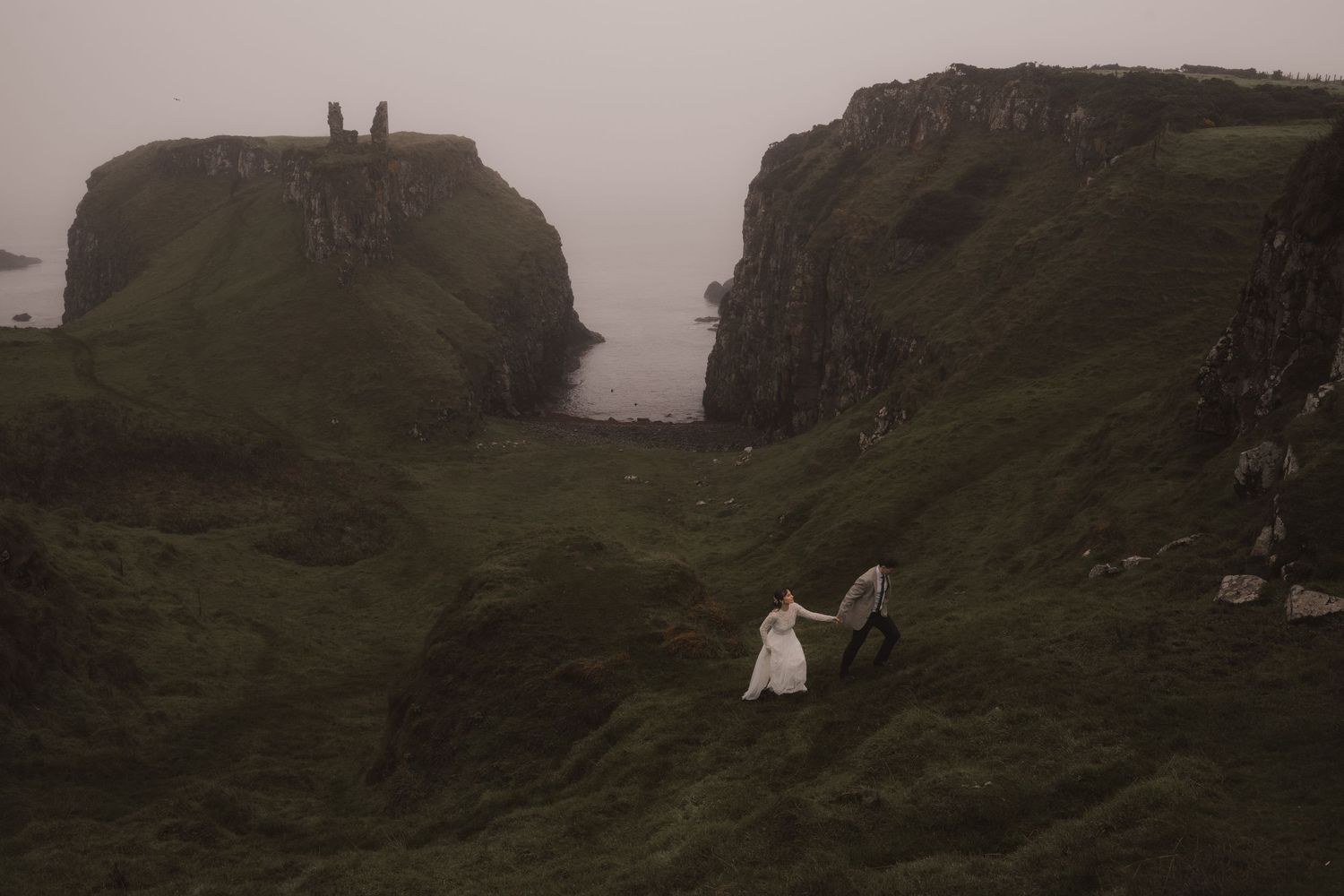 A romantic elopement wedding on Northern Ireland Coast with mountains, a castle and the sea in the background.
