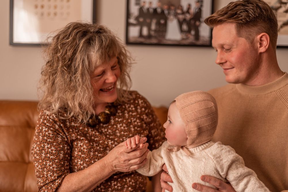 Heartwarming family moment as they interact with a baby in cream-colored knitwear.