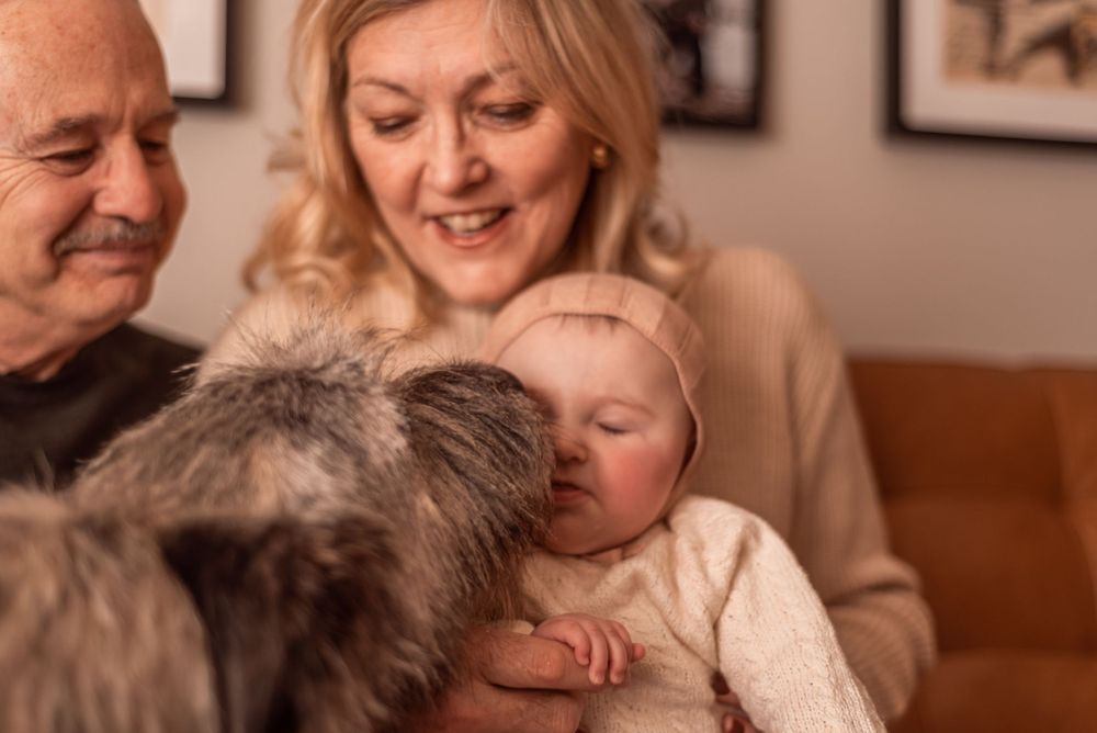 Intimate family moment with a sleeping baby in white knit clothing.