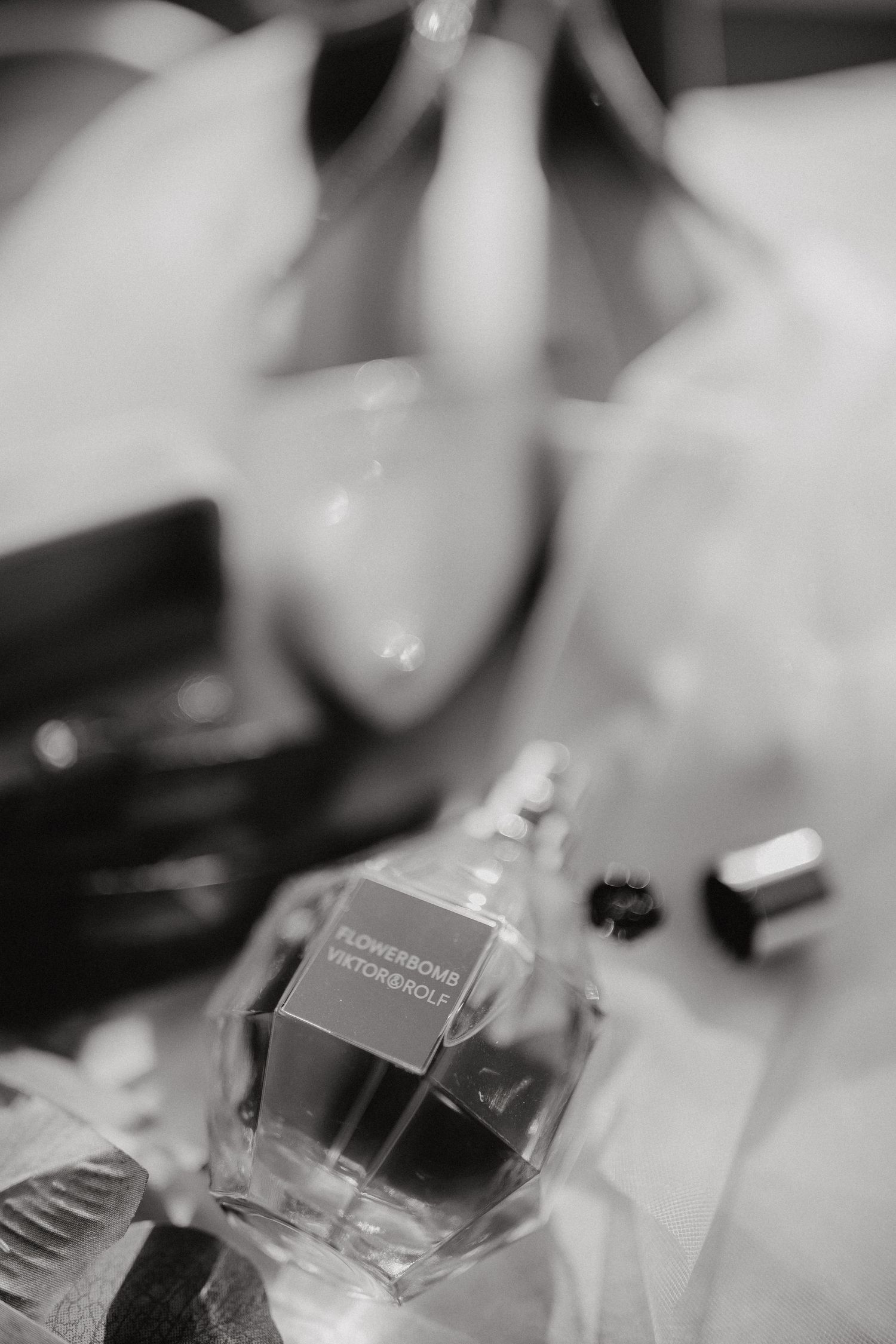 A blurred black and white photograph of a perfume bottle with soft focus and bokeh effects in the background.