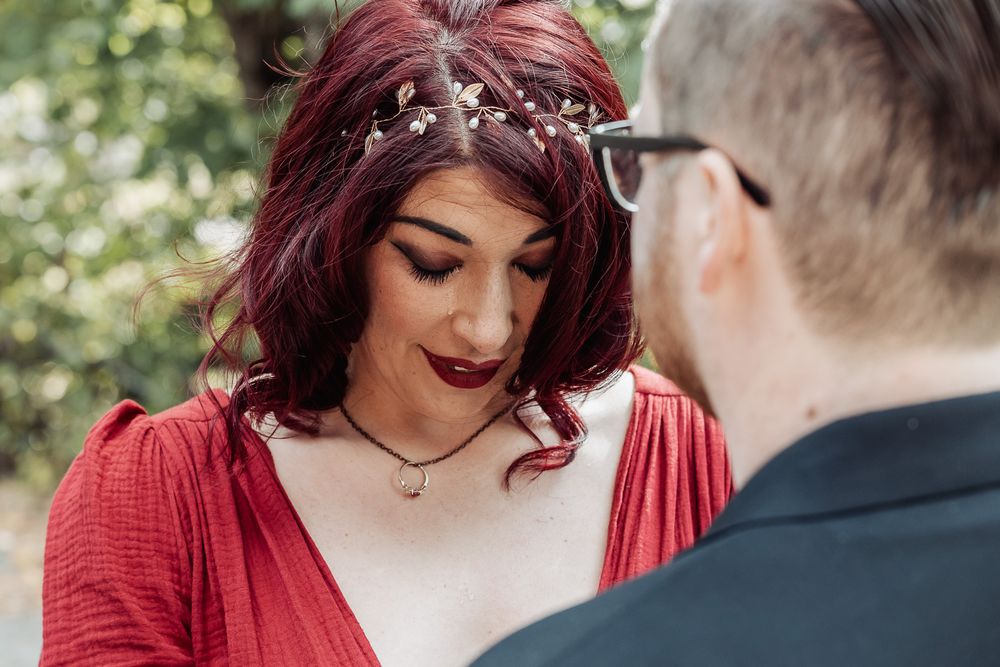 A romantic wedding moment captured outdoors with deep burgundy accents and delicate hair accessories.