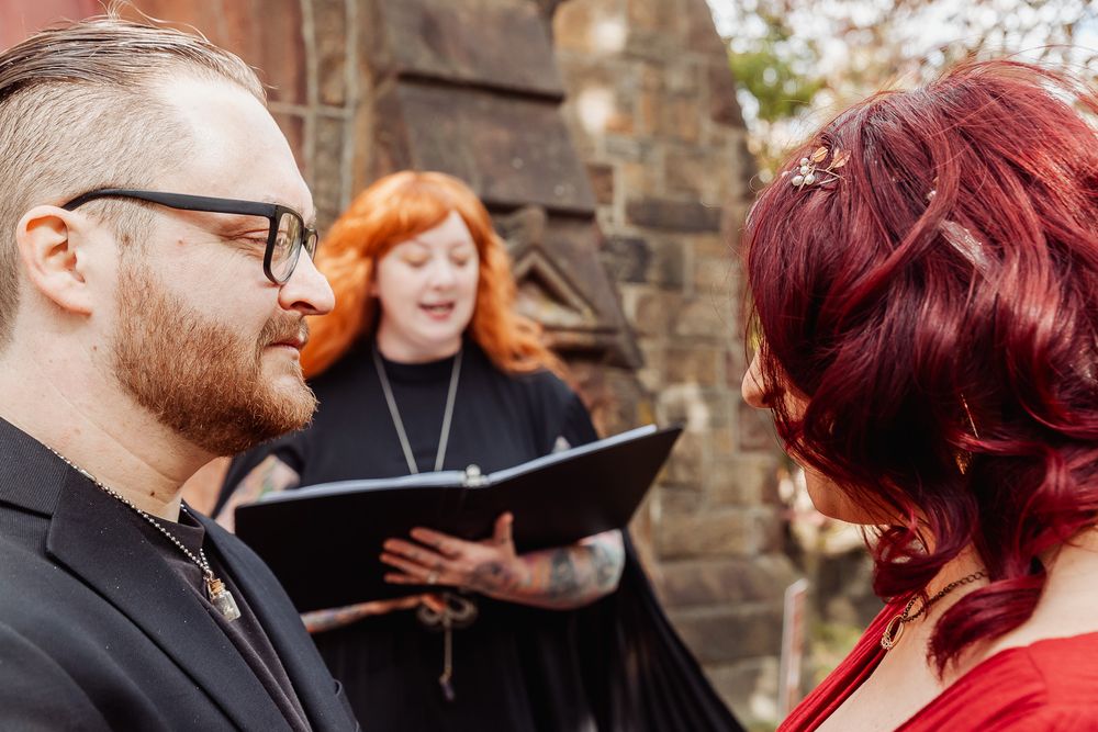 A wedding ceremony in progress with an officiant reading from a book outdoors.