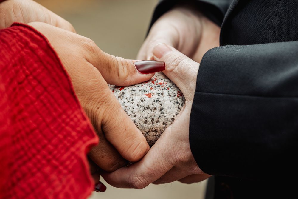 Close-up of hands exchanging a uniquely textured wedding ring during ceremony.