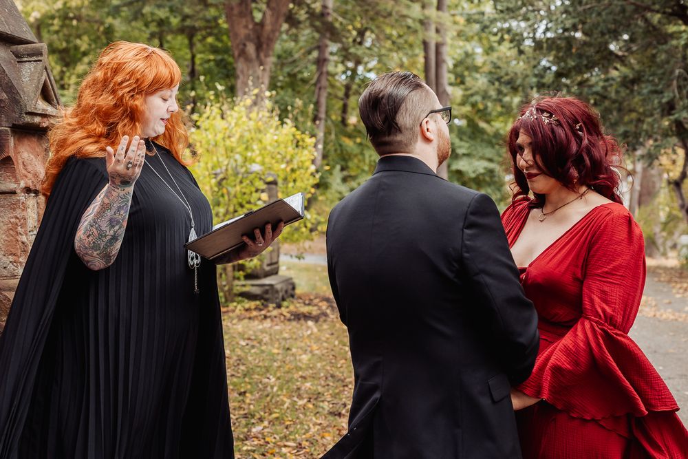 An autumn outdoor wedding ceremony with an officiant reading from a book.
