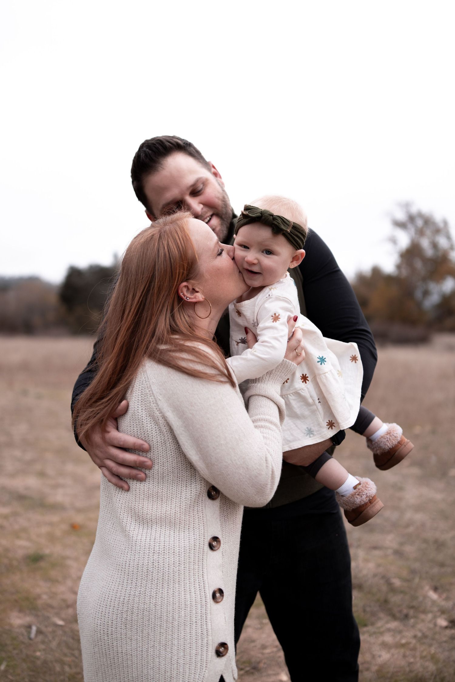 A couple in casual outfits embracing each other affectionately in a rustic outdoor field setting during autumn.