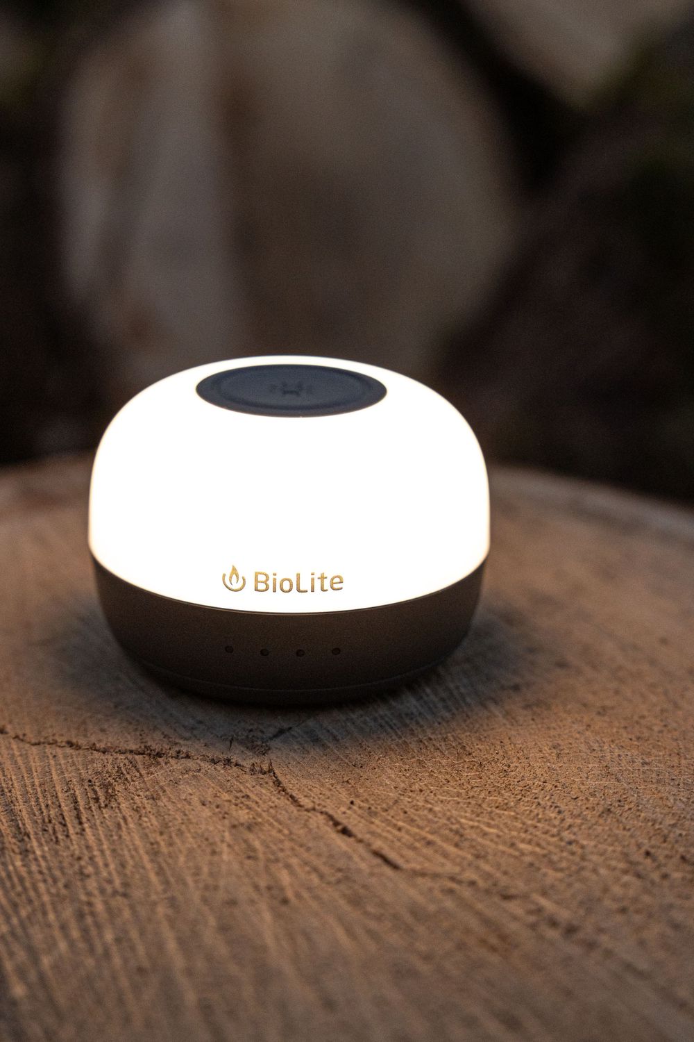 BioLite camping lantern sits on a wooden surface displaying its dome-shaped white and black design.
