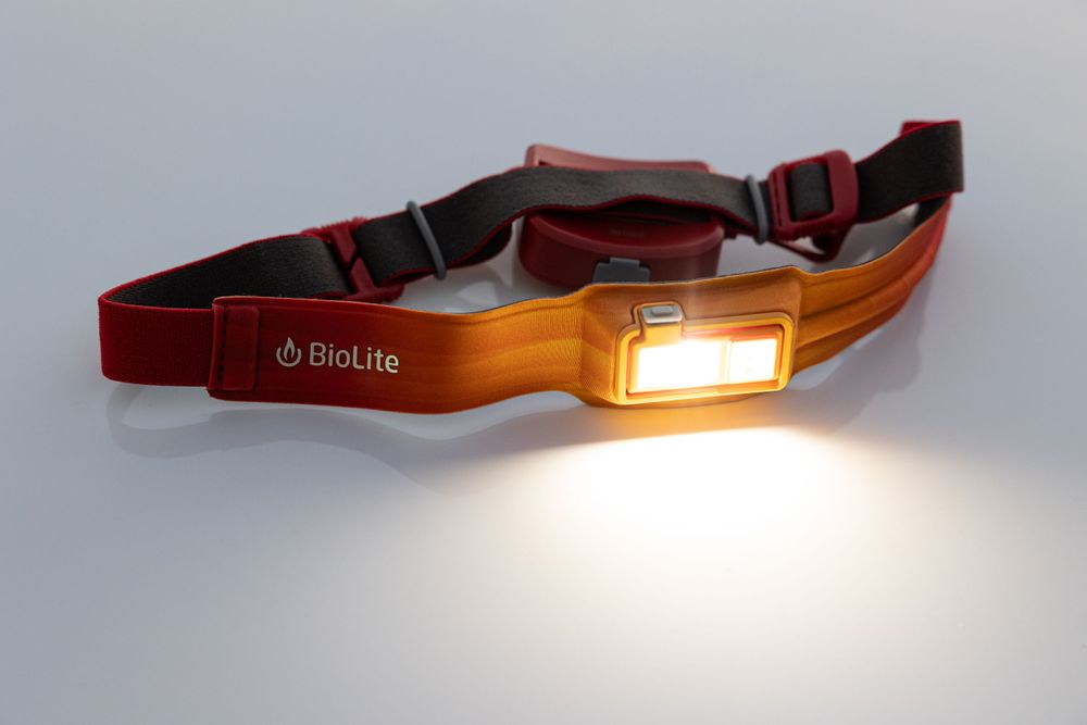 Red and orange BioLite headlamp strap with glowing LED light panel.