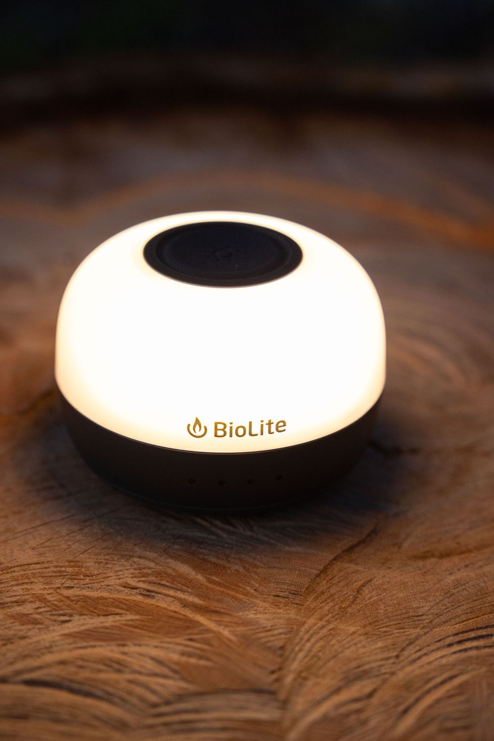 BioLite dome-shaped camping lantern illuminated on wooden surface.