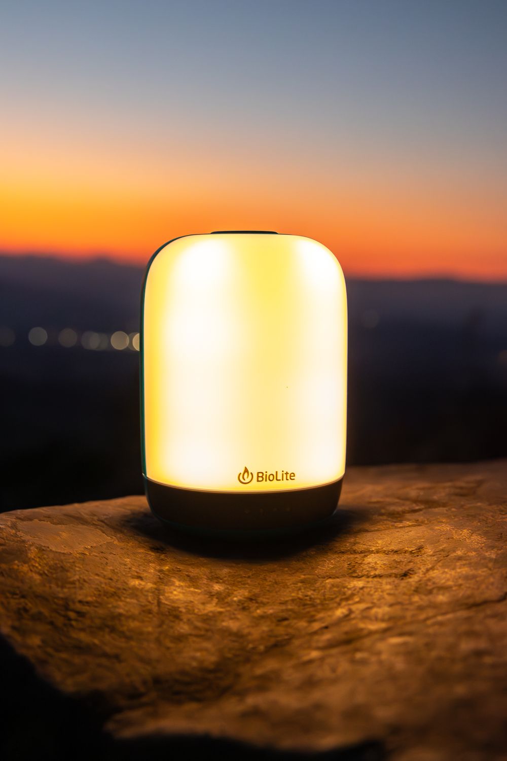 BioLite lantern emits warm light against a sunset mountain backdrop.