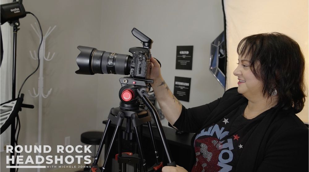 A photographer works with professional camera equipment and lighting setup in a studio setting.