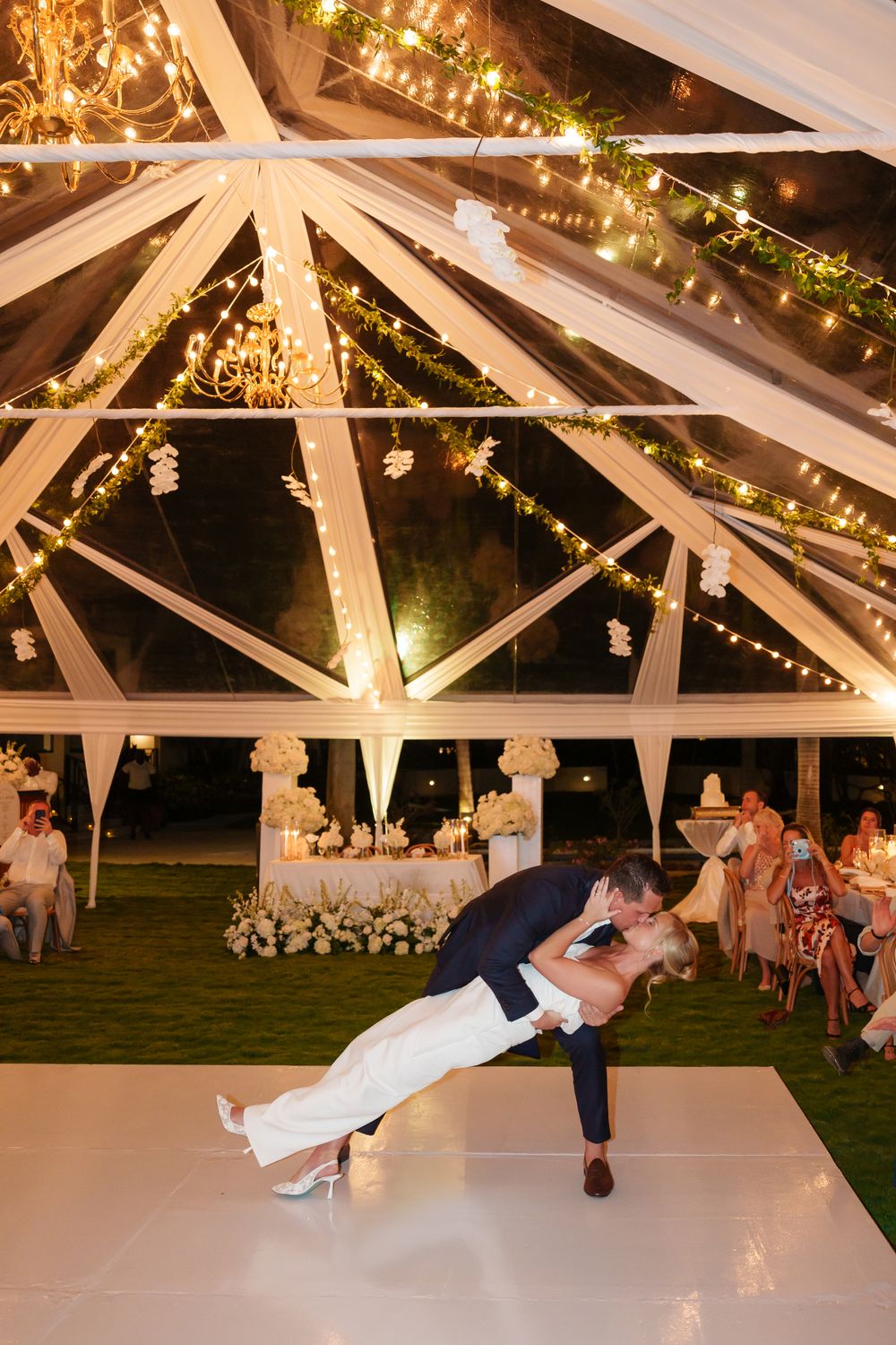 Dramatic dip dance move under a tent decorated with string lights and white fabric draping.