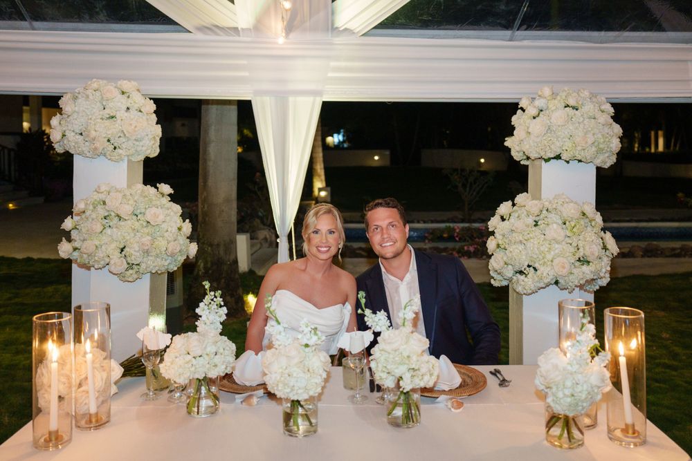 Reception table decorated with white floral arrangements and glowing candles for an intimate wedding celebration.