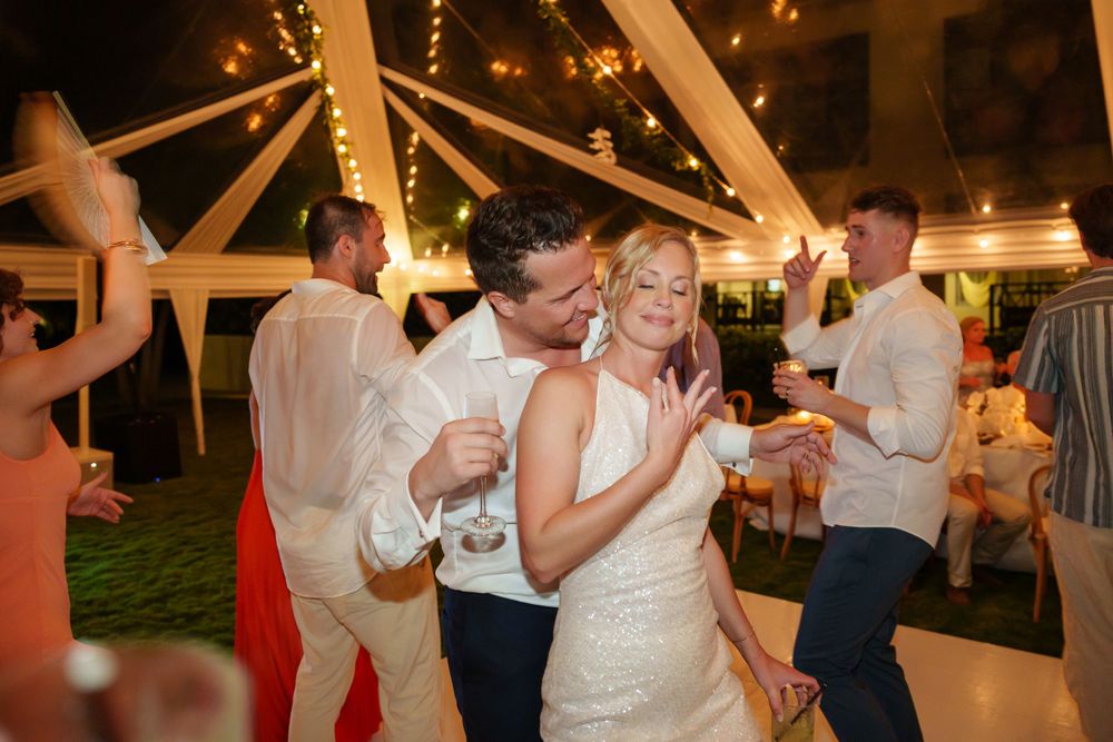 Reception party scene with dancing under string lights and tent decor.