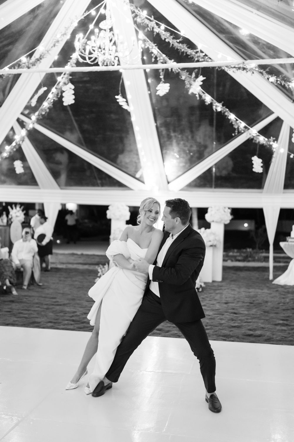 A romantic dance during a wedding reception under a beautifully decorated tent with hanging floral decorations.