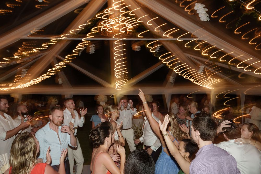 Wedding reception dance party with string lights and glowing decor illuminating a crowded dance floor.